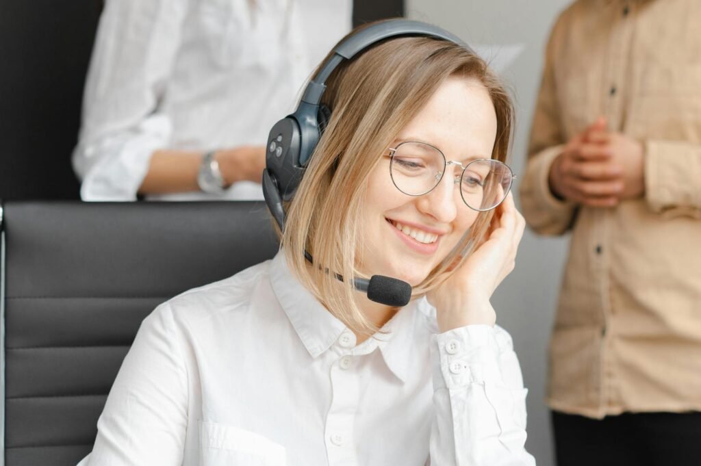 Contactar Asesorias Diaz Llauri A cheerful woman working at a call center, wearing a headset and glasses, providing excellent customer support.